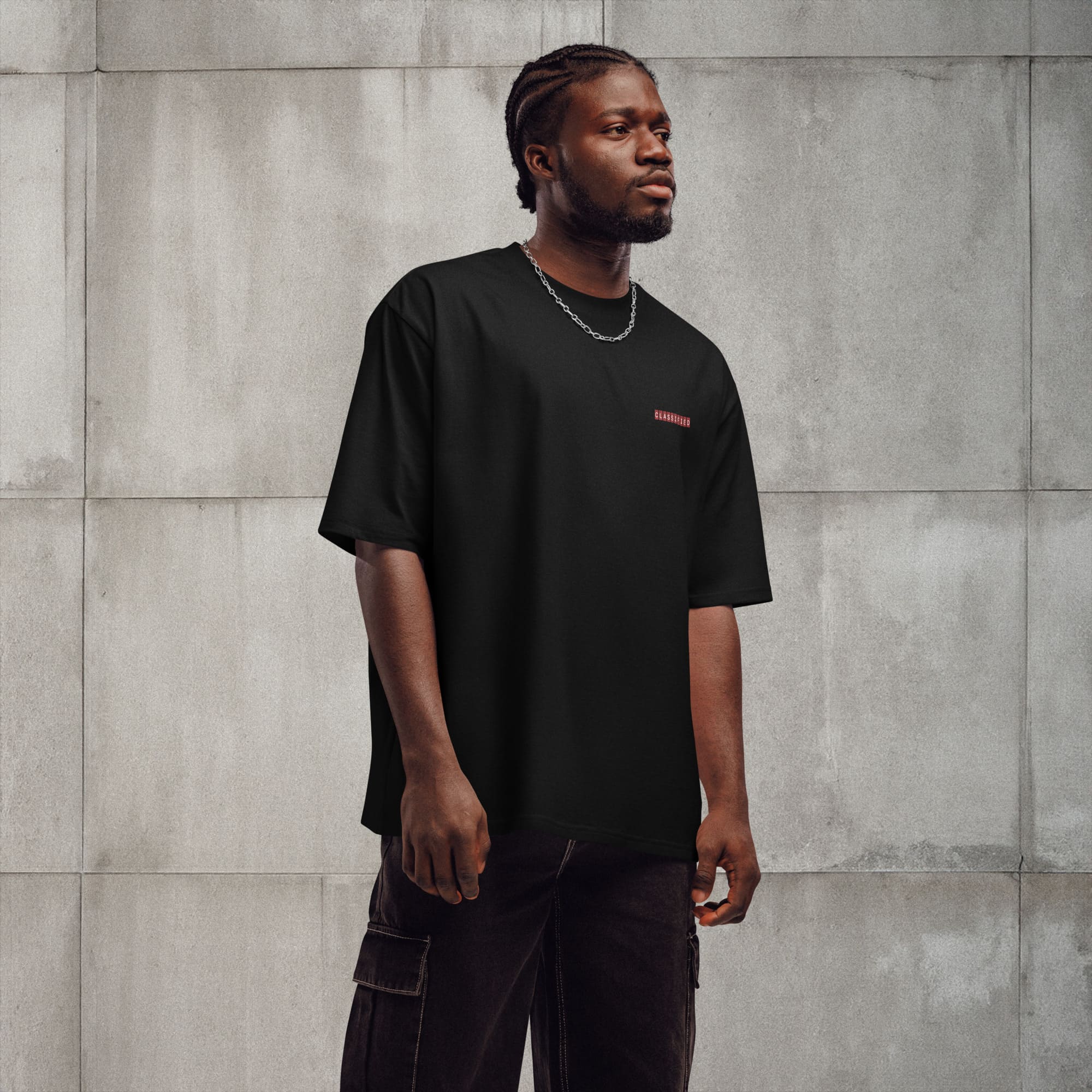 A man dressed in a black t-shirt and jeans stands confidently, showcasing a casual yet stylish appearance.