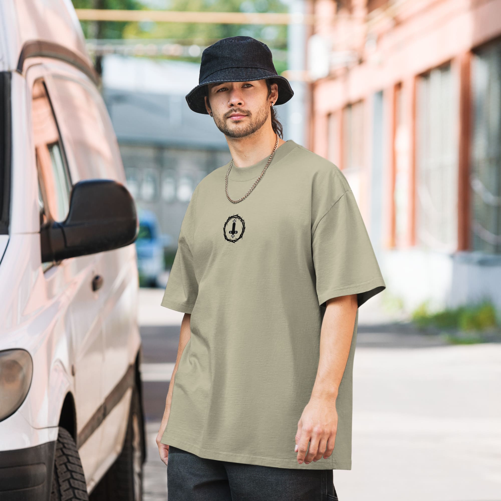 Person wearing a bucket hat and beige t-shirt stands on a street next to a white van.