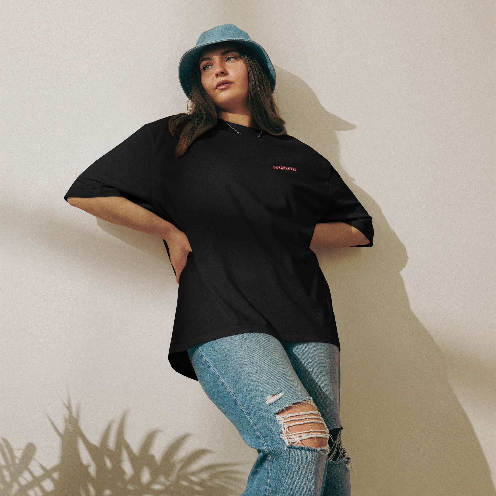 A woman dressed in a black t-shirt and jeans stands confidently, showcasing a casual yet stylish look.